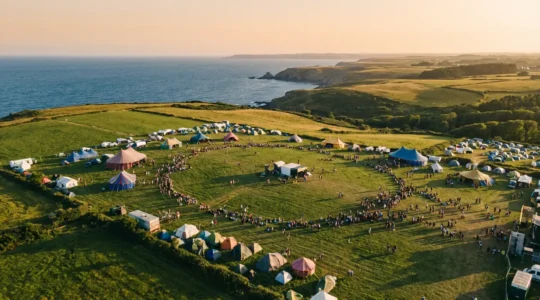Vue aérienne de la prairie de Landaoudec avec les scènes colorées du festival et la presqu'île de Crozon en arrière-plan